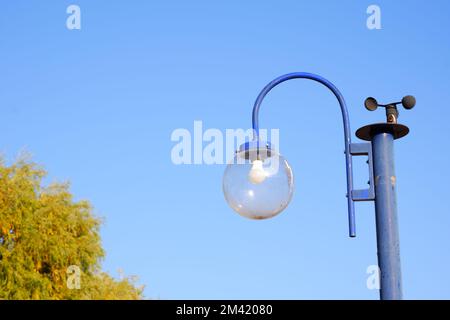 Blaue Straßenlampe mit Anamometer und blauem Himmel im Hintergrund an einem sonnigen Sommertag Stockfoto