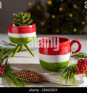 Keramik-Kaffeetassen auf einem Tisch mit weihnachtsdekor und Baum Stockfoto