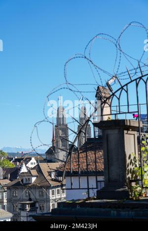 Blick auf die Kirche Grossmunster durch Stacheldraht auf einem Metalltor. Zürich, Schweiz. Stockfoto