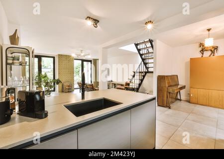 Eine Küche und Wohnzimmer in einem Haus mit Treppen, die in die zweite Etage führen, es gibt eine offene Treppe Stockfoto