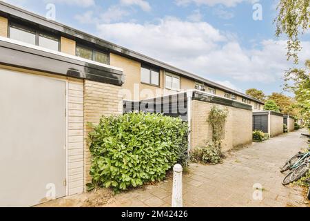 Ein Haus mit einem Fahrrad daneben auf dem Gehweg vor dem Haus ist blauer Himmel und weiße Wolken Stockfoto