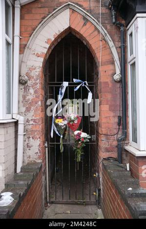 Clarence Road, Handsworth, 18. Dezember 2022. Die Polizei von West Midlands hat bestätigt, dass eine Leiche eines Kindes im Garten eines Anwesens an der Clarence Road in Handsworth, Birmingham, gefunden wurde. Die Polizei ist weiterhin auf dem Terrassengrundstück stationiert, wo florale Tribut an einem Tor, das zu den hinteren Gärten führt, hinterlassen wurden. Ein Grundstück hinter dem Haus wurde mit brauner Plane bedeckt, die den Tatort bedeckt. Ein 40- und 41-jähriger Mann wurde wegen Vernachlässigung angeklagt, weil er den Tod eines Kindes verursacht oder zugelassen hat. Quelle: Stop Press Media/Alamy Live News Stockfoto