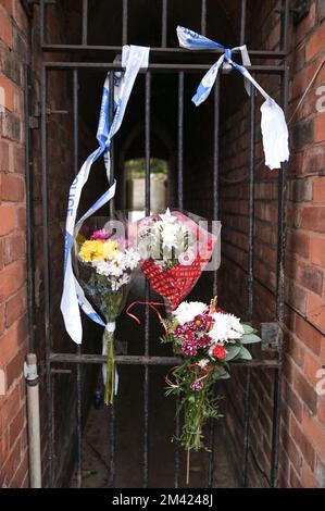 Clarence Road, Handsworth, 18. Dezember 2022. Die Polizei von West Midlands hat bestätigt, dass eine Leiche eines Kindes im Garten eines Anwesens an der Clarence Road in Handsworth, Birmingham, gefunden wurde. Die Polizei ist weiterhin auf dem Terrassengrundstück stationiert, wo florale Tribut an einem Tor, das zu den hinteren Gärten führt, hinterlassen wurden. Ein Grundstück hinter dem Haus wurde mit brauner Plane bedeckt, die den Tatort bedeckt. Ein 40- und 41-jähriger Mann wurde wegen Vernachlässigung angeklagt, weil er den Tod eines Kindes verursacht oder zugelassen hat. Quelle: Stop Press Media/Alamy Live News Stockfoto