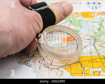 Hand hält einen Kompass auf einer OL-Karte Stockfoto