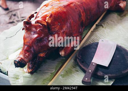 Kopfschuss des frisch zubereiteten Allzeit-Favoriten, des beliebten köstlichen, gebratenen, knusprigen ganzen Schweins oder Lechon Baboy auf Bananenblatt. Ausgewählter Fokus. Stockfoto