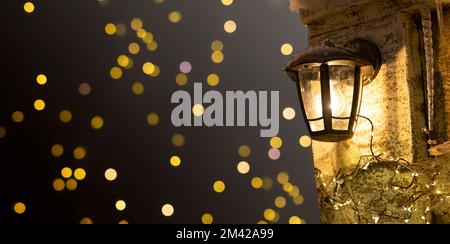 Straßenlaterne, an der Wand montiertes gelbes, warmes Licht im kalten Winter. Banner, Weihnachtshintergrund. Hochwertiges Foto Stockfoto