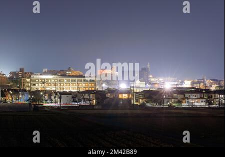 Dichte Gebäude, hell beleuchtet am Stadtrand bei Nacht Stockfoto