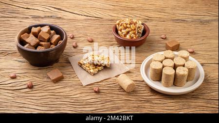 Typisch brasilianische Süßigkeiten auf einem Holztisch. Doce de leite oder dulce de leche, pe de moleque und pacoca. Stockfoto