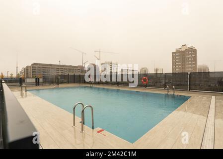 Ein neu gebauter rechteckiger Gemeinschaftspool in einem neuen Stadtteil an einem sintflutartigen Regentag Stockfoto