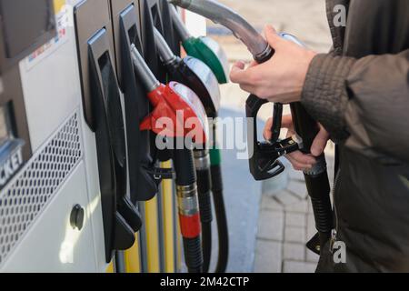 Verwendung von Fülldüsen an einer Tankstelle. Die Frau nimmt eine Füllpistole. Selektiver Fokus Stockfoto