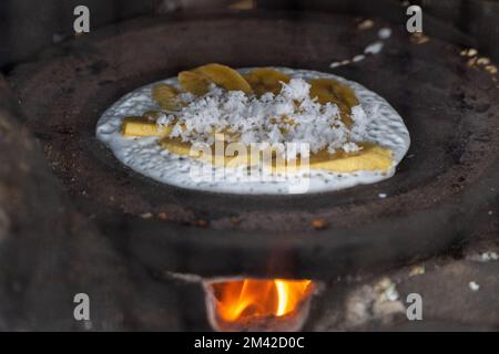 Einer der traditionellen Snacks von Tabanan, Bali, aus Reismehl, das auf einem Tonofen geröstet wird. Scheiben von Banane und geriebener Kokosnuss werden hinzugefügt, um ein hinzuzufügen Stockfoto