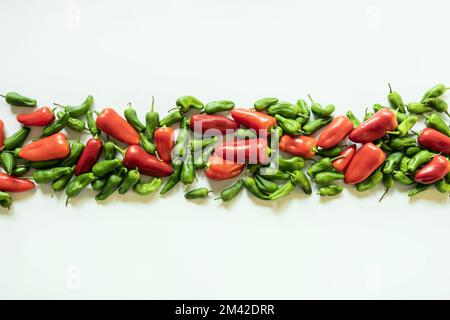 Eine Linie frischer roher roher Paprika und grüner Paprika auf einer weißen Oberfläche Stockfoto