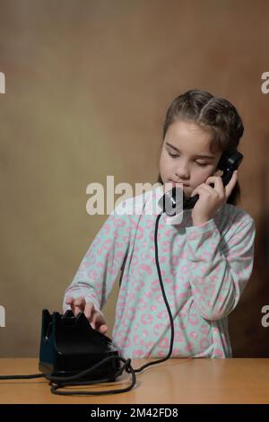 Porträt eines Mädchens mit Telefon. Das Teenager-Mädchen wählt eine Nummer auf einem alten Retro-Telefon Stockfoto