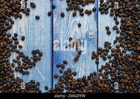 Blauer Holzhintergrund mit Hunderten gerösteter Kaffeebohnen an den Kanten Stockfoto