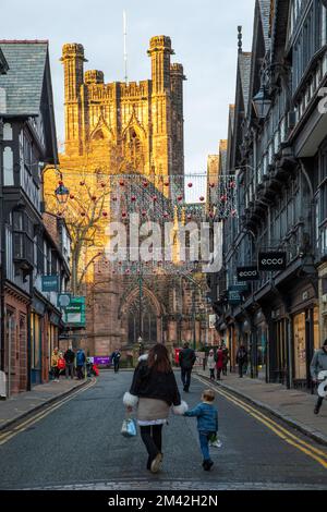 Blick auf die Kathedrale von Chester entlang der St. Werburgh Street während der Weihnachtsbeleuchtung mit Weihnachtseinkaufsmöglichkeiten Stockfoto