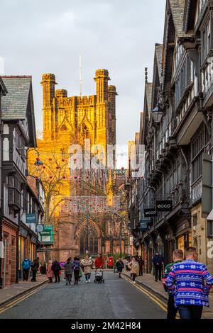 Blick auf die Kathedrale von Chester entlang der St. Werburgh Street während der Weihnachtsbeleuchtung mit Weihnachtseinkaufsmöglichkeiten Stockfoto