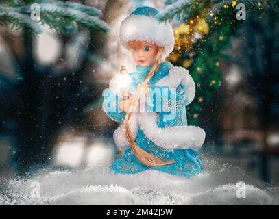 Spielzeugpuppe Snow Maiden im Schnee mit einer Taschenlampe in der Hand Stockfoto