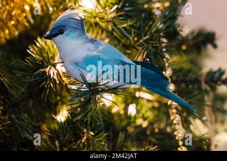 Blue Jay Weihnachtsschmuck in einem künstlichen Weihnachtsbaum mit Weihnachtslicht im Hintergrund Stockfoto