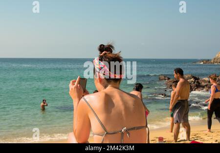 Frau, die ein Foto vom Strand in Puerto Escondido, Mexiko macht Stockfoto