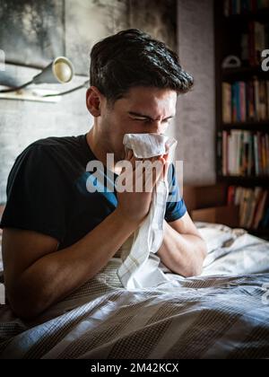Junger Mann, der sich die Nase mit Taschentuch putzt Stockfoto