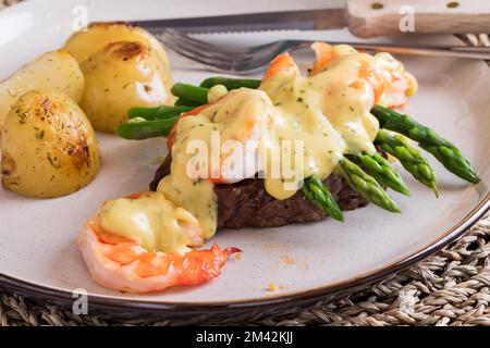 Köstliches Steak Oscar mit Jumbo-Garnelen serviert mit gebratenen Kartoffeln. Stockfoto