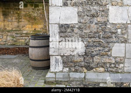 Ein Teil eines alten Innenhofs, eine Steinmauer und ein altes großes Fass für Wein. Kreativer Hintergrund Stockfoto