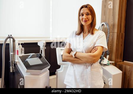 Porträt einer Kosmetikerin mit Massagegerät im Salon. Kosmetiker in einem Schönheitssalon. Kosmetologe Dermatologe in einer Kosmetikklinik. Gesichtsbehandlung Stockfoto