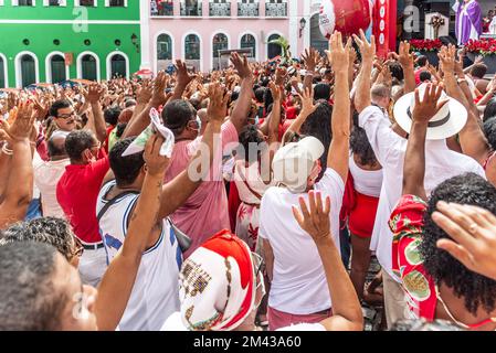 Salvador, Bahia, Brasilien - 04. Dezember 2022: Gläubige Katholiken von Santa Barbara erheben ihre Waffen zum Himmel zu Ehren des Weihnachtsmanns. Pelourinho, Salvador, Ba Stockfoto