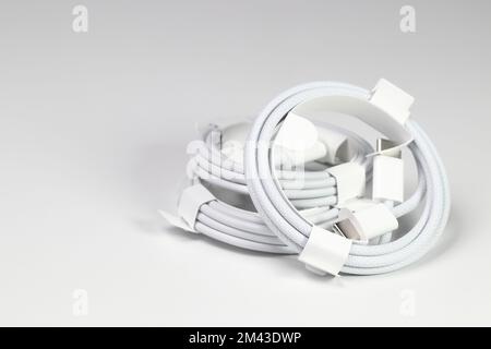 Neues weißes USB-Ladekabel, kompatibel mit vielen Geräten, spiralförmig verpackt, isoliert auf weißem Hintergrund. Stockfoto