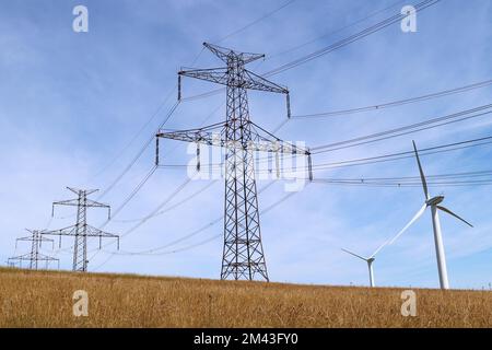 Hochspannungsleitungen und Windkraftanlagen Stockfoto