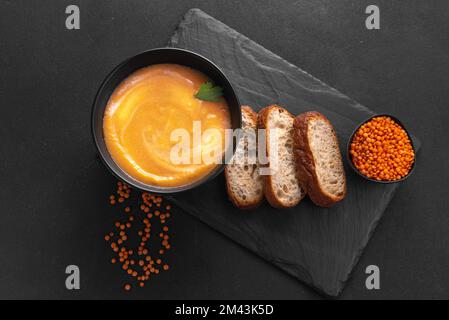 Rote Linsensuppe auf dunklem Hintergrund, Draufsicht. Traditionelle nahöstliche, türkische und Ramadan-Küche. Vegane Küche. Linsensuppe mit roten Linsen Stockfoto