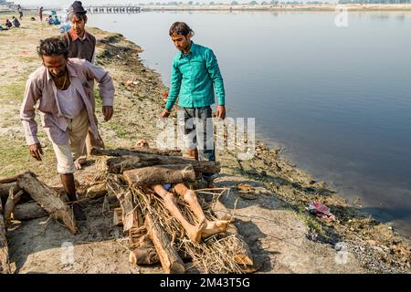 Als Teil einer Einäscherungszeremonie eine Tote auf Feuerholz am Ufer des Flusses Yamuna zu legen Stockfoto