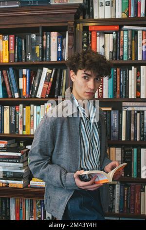 Junger Mann hält Buch in der Buchhandlung Stockfoto