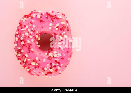 Rosafarbener Donut mit Streuseln auf pinkfarbenem Pastellhintergrund. Ein süßer rosa Donut. Draufsicht. Speicherplatz kopieren Stockfoto