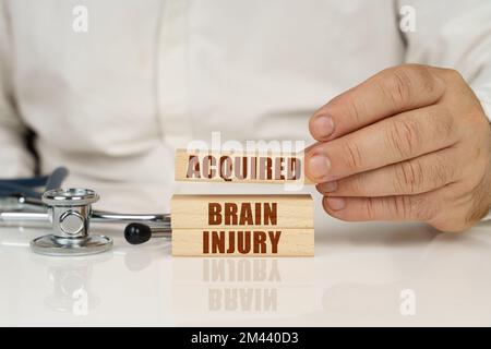 Medizinisches Konzept. Auf einer weißen Oberfläche, einem Stethoskop und Holzplatten mit der Aufschrift "erworbene Hirnverletzung" Stockfoto