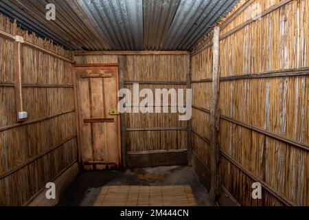 Innenansicht eines Schilfhauses, das in einigen Teilen Afrikas üblich ist, mit Schilfwänden, gebrannten Betonböden und Zinkblech-Dach Stockfoto