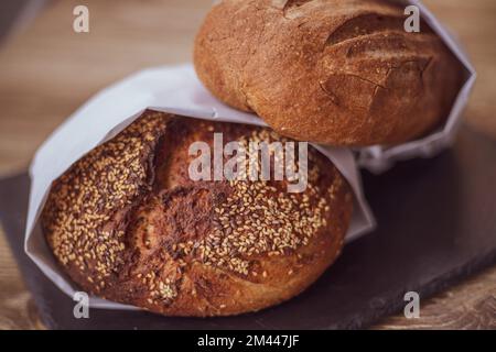 Frisches Brot in einer Papiertüte auf einem Holztisch. Das Konzept der Naturprodukte. Glutenfreies Brot. Stockfoto