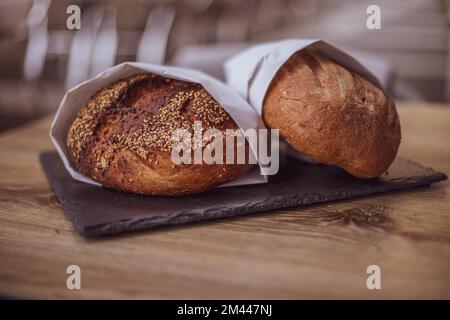 Frisches Brot in einer Papiertüte auf einem Holztisch. Das Konzept der Naturprodukte. Glutenfreies Brot. Stockfoto