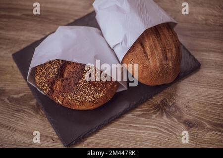 Frisches Brot in einer Papiertüte auf einem Holztisch. Das Konzept der Naturprodukte. Glutenfreies Brot. Stockfoto