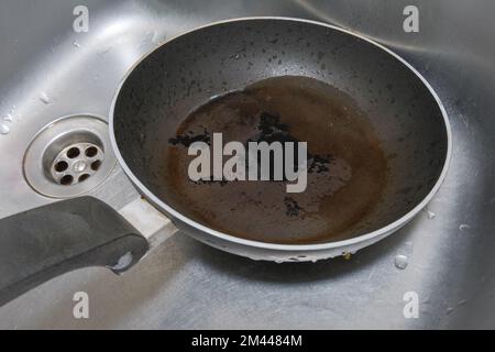 Verbrannte Bratpfanne im Spülbecken. Eine Nahaufnahme. Stockfoto