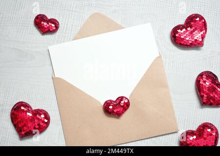 Leere weiße Grußkarte mit braunem Umschlag und Herzen auf Marmortisch. Modellkonzept Valentinstag Stockfoto