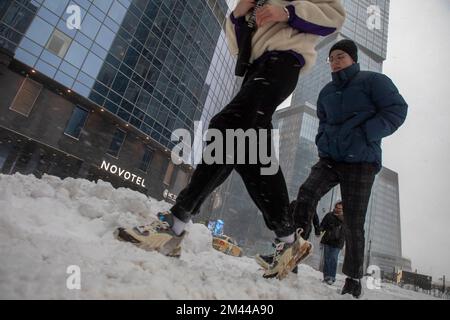 Moskau, Russland. 18.. Dezember 2022. Menschen gehen auf dem Moskauer International Business Center 'Moskau-Stadt im Hintergrund von Wolkenkratzern während abnormer Schneefälle im Zentrum von Moskau, Russland Stockfoto