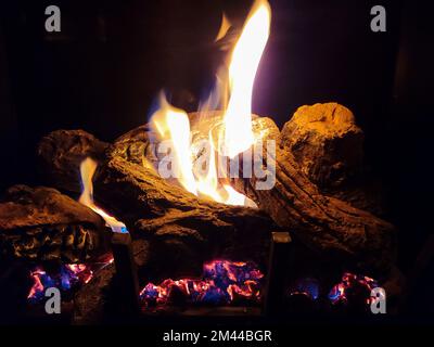 Glühende Baumstämme im Kamin mit Flammen und Glut Stockfoto