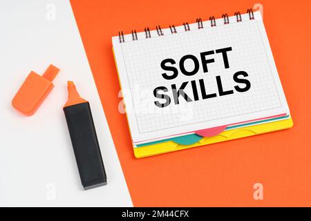 Geschäfts- und Finanzkonzept. Auf einer weiß-orangefarbenen Oberfläche liegen ein Marker und ein Notizblock mit der Aufschrift „SOFT SKILLS“ Stockfoto