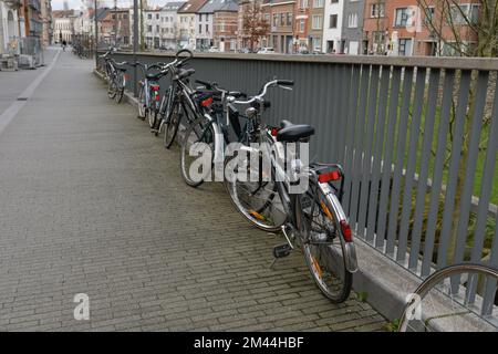 Leuven. Vlaams-Brabant - Belgien 02-01-2021. Fahrräder in der Stadt. Anzahl der Fahrräder, die an einem Metallzaun auf einer leeren Straße geparkt sind Stockfoto