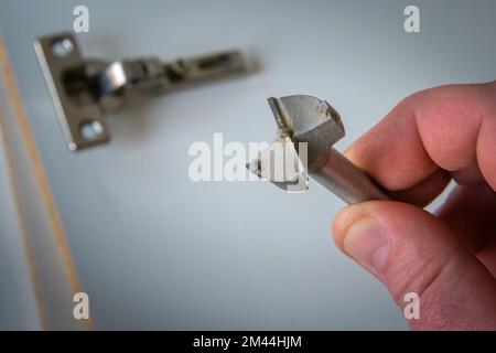 Spezialwerkzeug zur Montage von Möbelbeschlägen. Scharnier an modernem Schrank befestigt. Stockfoto