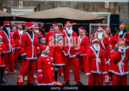 Breda, Niederlande. 18.. Dezember 2022. Personen, die Weihnachtsmannkostüme tragen, werden während der Präsentation der Veranstaltung zugesehen. Heute finden in vielen Städten in Ländern der ganzen Welt Santa Run-Veranstaltungen statt. In der niederländischen Stadt Breda liefen zweihundert Menschen, einschließlich Eltern mit ihren Kindern, während der Rotary Santa Run rund 3 km in Weihnachtskostümen. Die einmal jährlich stattfindende Veranstaltung wurde von der Stiftung „Rotary Santa Run“ organisiert. Die Veranstaltung brachte mindestens 8.000â‚¬ für zwei lokale Wohltätigkeitsorganisationen ein, die Stiftung "Youth Breakfast Breda Foundation" und die Stiftung "Het Bonte Perdje", die jungen Menschen dieses Angebot bieten soll Stockfoto