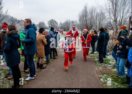 Breda, Niederlande. 18.. Dezember 2022. Man sieht, wie die Weihnachtsmann-Läufer an der Ziellinie klatschen. Heute finden in vielen Städten in Ländern der ganzen Welt Santa Run-Veranstaltungen statt. In der niederländischen Stadt Breda liefen zweihundert Menschen, einschließlich Eltern mit ihren Kindern, während der Rotary Santa Run rund 3 km in Weihnachtskostümen. Die einmal jährlich stattfindende Veranstaltung wurde von der Stiftung „Rotary Santa Run“ organisiert. Die Veranstaltung brachte mindestens 8.000â‚¬ für zwei lokale Wohltätigkeitsorganisationen, die Stiftung "Youth Breakfast Breda Foundation" und die Stiftung "Het Bonte Perdje", die jungen Menschen mit Behinderungen anbieten soll, ein Stockfoto