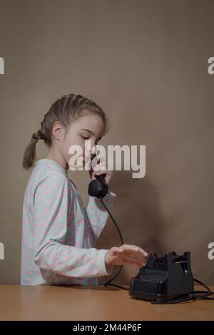 Retro-Porträt eines Mädchens mit altem Telefon. Das Teenager-Mädchen wählt eine Nummer auf einem alten Telefon Stockfoto