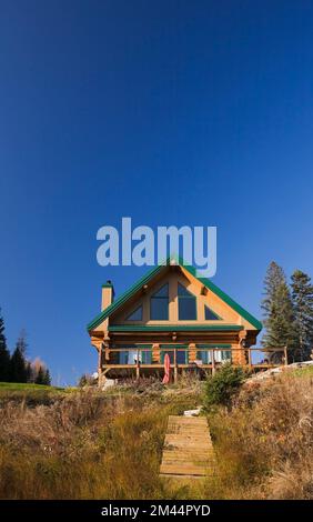 Rückansicht eines zweistöckigen Blockhauses im A-Rahmen-Stil mit grüner Verkleidung im Herbst. Stockfoto